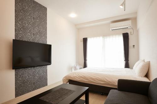 a bedroom with a bed and a tv on a wall at New Normal Hotel in NAGO ニューノーマルホテルイン名護 in Nago