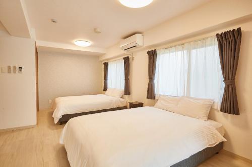 a hotel room with two beds and a window at New Normal Hotel in NAGO ニューノーマルホテルイン名護 in Nago