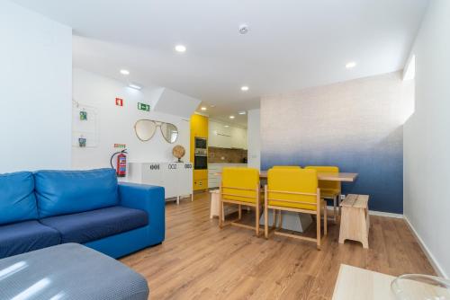 sala de estar con sofá azul y sillas amarillas en Dude Beach Hostel, en Figueira da Foz