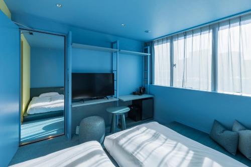 a blue room with a bed and a tv at toggle hotel suidobashi TOKYO in Tokyo