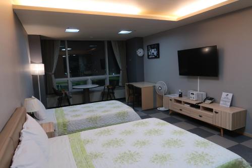 a hotel room with two beds and a flat screen tv at Prime Guesthouse in Incheon