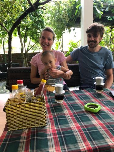 Dos hombres y un bebé sentados en una mesa de picnic. en Cat Ba Countryside Homestay, en Cat Ba