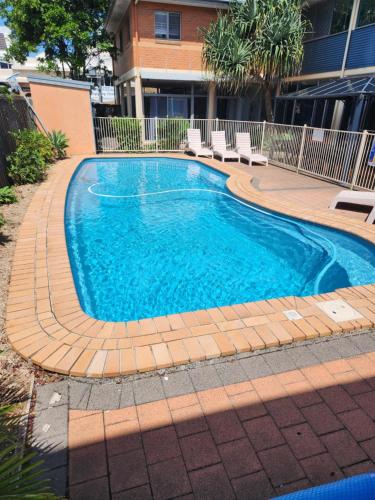 a swimming pool with chairs around it in a building at Jetty Blue Backpackers in Coffs Harbour