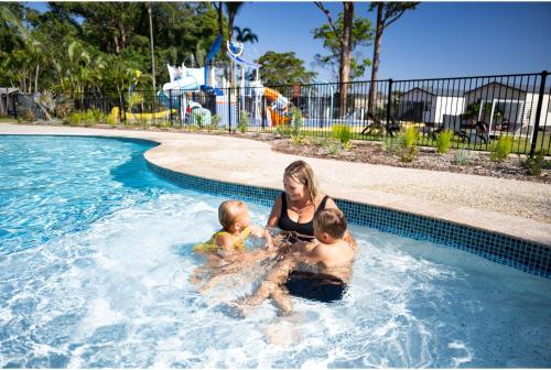 a woman and two babies in a swimming pool at Discovery Parks - Forster in Tuncurry