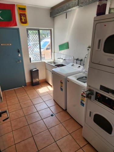 a kitchen with a sink and a washer and dryer at Jetty Blue Backpackers in Coffs Harbour