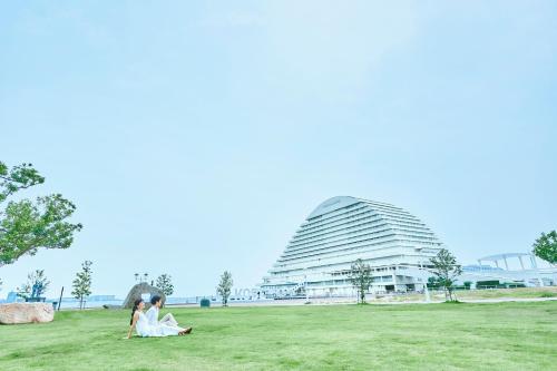 two people sitting on the grass in front of a building at Kobe Meriken Park Oriental Hotel in Kobe