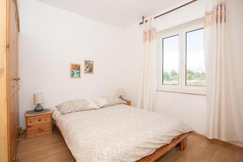 a white bedroom with a bed and a window at House MG in Skradin