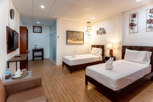 um quarto de hotel com duas camas e um sofá em MADISON GARDEN AND RESIDENCES em Panglao