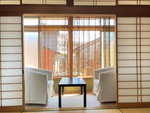 a table and chairs in a room with a window at Guesthouse Namaste in Kanazawa