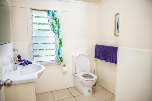 a bathroom with a toilet and a sink and a window at Coral Sands Apartments in Rarotonga