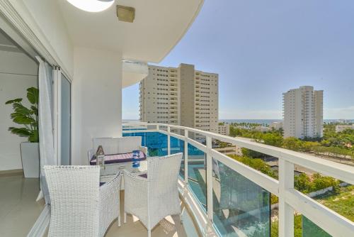 a balcony with white chairs and a view of the city at Sunset View 2BR Apartamento Juan Dolio Las Velas in Juan Dolio