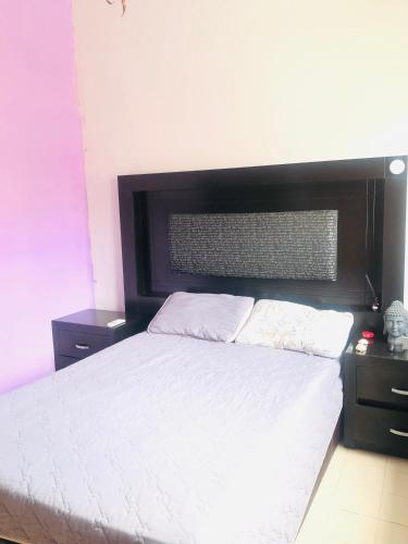 ein Schlafzimmer mit einem weißen Bett mit einem schwarzen Kopfteil in der Unterkunft Tláloc House in Tuxtla Gutiérrez