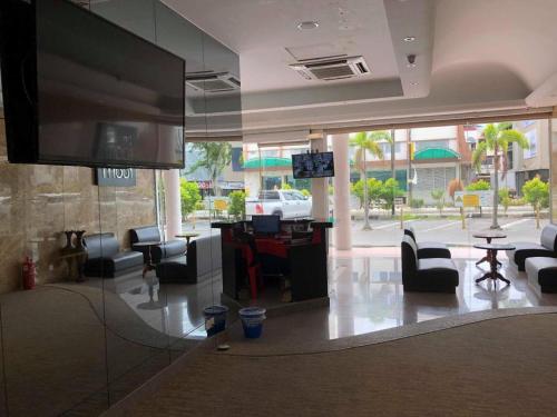 een lobby met een groot televisiescherm en meubilair bij The Room Hotel in Miri