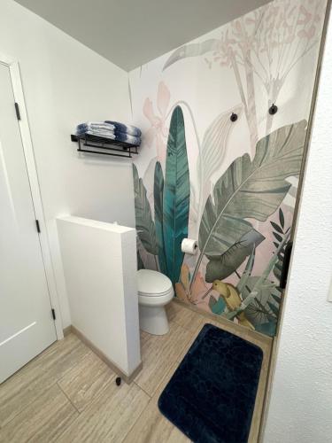 a bathroom with a toilet and a mural of plants at Hale O Malu at Kaloli Point in Keaau