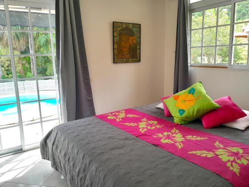 Schlafzimmer mit einem Bett mit rosa und grünen Kissen in der Unterkunft MOOREA VILLA KAHAIA in Teavaro