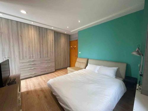 a bedroom with a large white bed and a blue wall at FengJia Pleasure Life 1 in Taichung