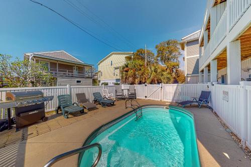 a swimming pool in a yard with chairs and a fence at Sun Sprinkles in Kure Beach