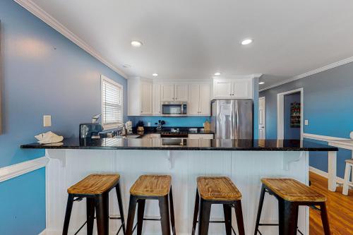 a kitchen with three wooden stools at a counter at Sun Sprinkles in Kure Beach