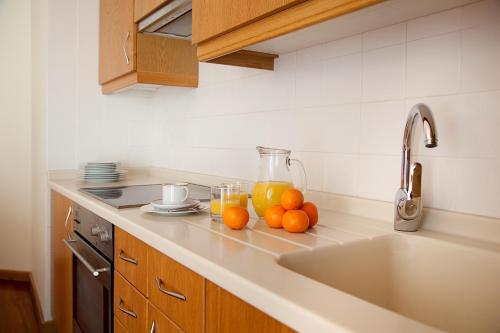 a kitchen counter with oranges and a pitcher of juice at MS Aparthotel in Linda-a-Velha
