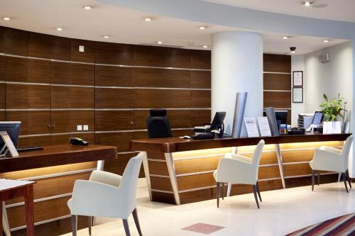 a lobby with a reception desk and white chairs at MS Aparthotel in Linda-a-Velha