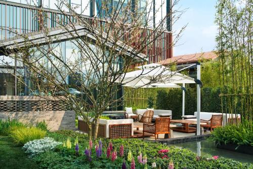 a garden with chairs and an umbrella in front of a building at Mumian Chengdu, in The Unbound Collection by Hyatt in Chengdu