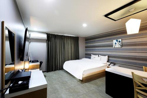 ein Hotelzimmer mit einem Bett, einem Schreibtisch und einem TV in der Unterkunft White Tourist Hotel in Jeonju