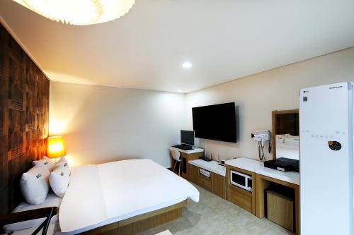 a hotel room with a bed and a flat screen tv at White Tourist Hotel in Jeonju