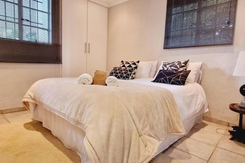 ein Schlafzimmer mit einem großen Bett mit weißer Bettwäsche und Kissen in der Unterkunft Herbie's Hideout: 1 Bed Cottage W/ View and Pool in Bothaʼs Hill