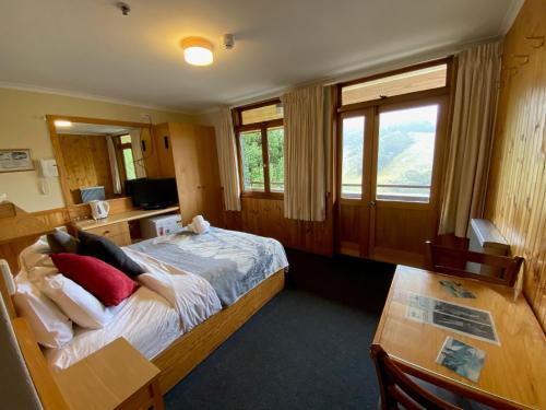 a bedroom with a bed and a desk and a table at Candlelight Lodge in Thredbo