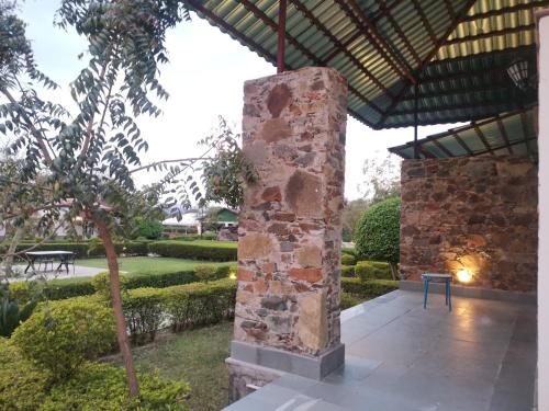 a stone pillar in the middle of a garden at Astroport Sariska Treetop by Eight Continents in Tehla