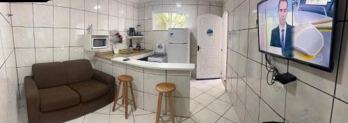 a small kitchen with a chair and a television at SUITEs E FLATs MONTE ALTO ARRAIAL DO CABO in Arraial do Cabo