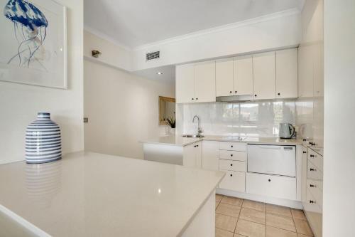 a kitchen with white cabinets and a vase on the counter at The Masthead Iluka Apartment Luxury and Style in Palm Beach