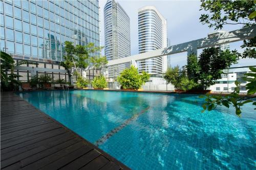 a swimming pool in a city with tall buildings at Sabai Sathorn Service Apartment in Bangkok