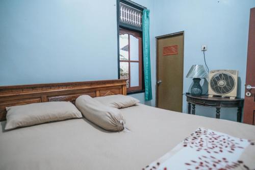 a bedroom with a bed with pillows and a fan at Agus Hidden Homestay - Banjar Sweet Village in Banyuwangi