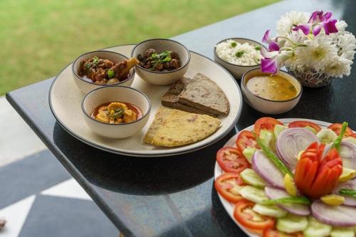 a table topped with plates of food on a table at amã Stays & Trails Abhay Manor Kaali Toonk, Udaipur in Ghānerao