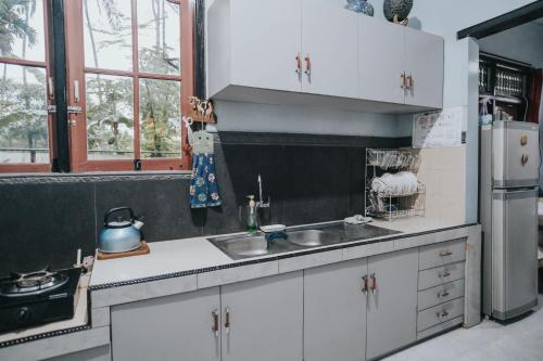 a kitchen with white cabinets and a sink and a refrigerator at Agus Hidden Homestay - Banjar Sweet Village in Banyuwangi