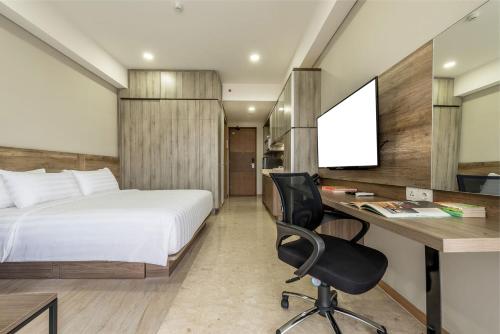 a bedroom with a bed and a desk with a computer at Grande Valore Hotel Cikarang in Cikarang