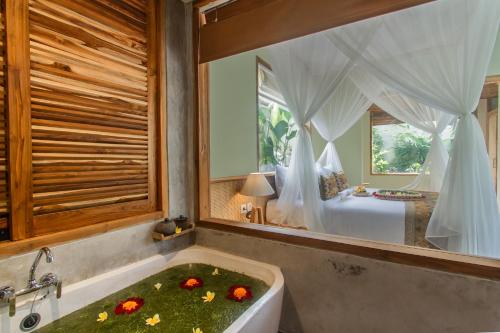a bathroom with a bath tub with flowers in it at Reswaha Villas by Pramana Villas in Ubud