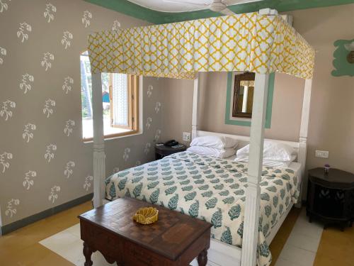 a bedroom with a canopy bed with a wooden table at Casa Anjuna in Anjuna