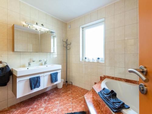 uma casa de banho com uma banheira, um lavatório e um espelho. em Mountain Idyll by the River High-End Apartment in the Ötztal Valley 