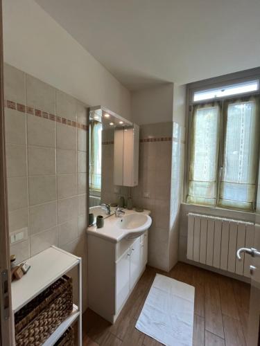 ein weißes Badezimmer mit einem Waschbecken und einem Spiegel in der Unterkunft La Maison di Gabriella e Alfredo in Edolo