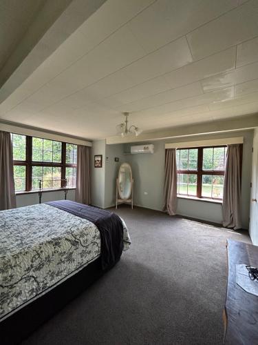una camera con letto e alcune finestre di Arden Country House BnB a Dunedin