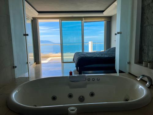 a bath tub in a bathroom with a view of the ocean at Conchas chinas sunset view in Puerto Vallarta