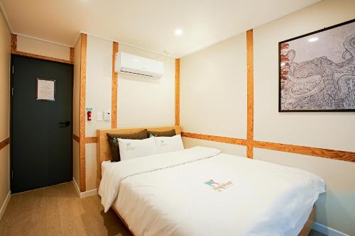 - une chambre avec un lit blanc et une peinture murale dans l'établissement Geonmaek Stay, à Mokpo