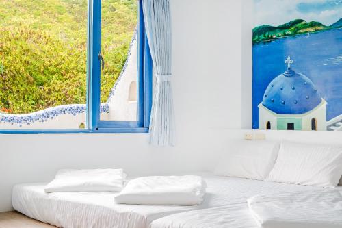 a bed in a room with a window at White Lighthouse in Xiaoliuqiu