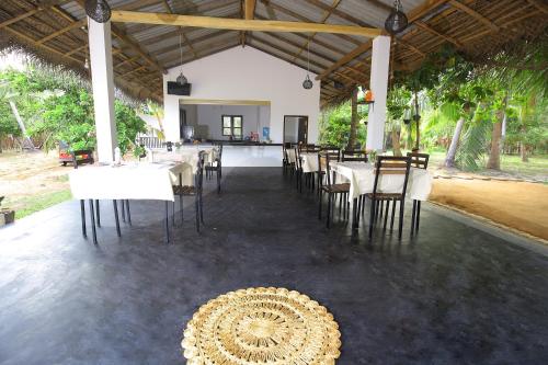 a dining room with white tables and chairs and a table and chairsearcher at Rekawa Lagoon Resort in Tangalle
