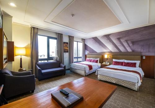 a hotel room with two beds and a chair and a table at Golden Tulip - Aesthetics in Zhunan