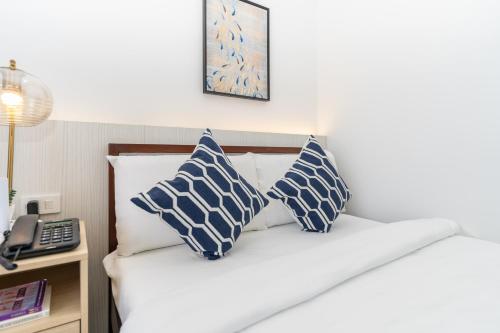 a bed with blue and white pillows and a phone at 732 Express Condotel, 3 Minutes to Airport, with Gym & Pool FAST WI-FI, Free Netflix in Pusok