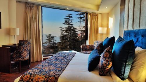 a bedroom with a bed with a large window at Royale Retreat Hotel & Spa Near Mall Road in Shimla