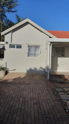 ein weißes Haus mit einer steinernen Einfahrt in der Unterkunft Refreshing Space in Eden Glen, Johannesburg, SA in Edenvale